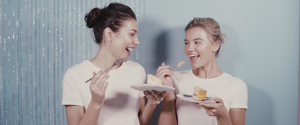 models looking happy and eating cake against a blue background