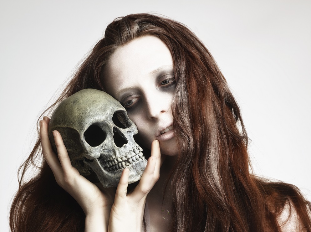 A ghostly bride lovingly holding a skull.