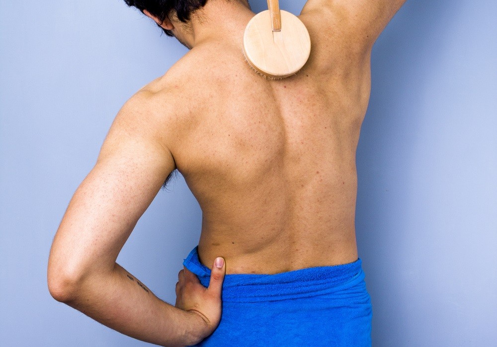 Man in towel scrubbing his back