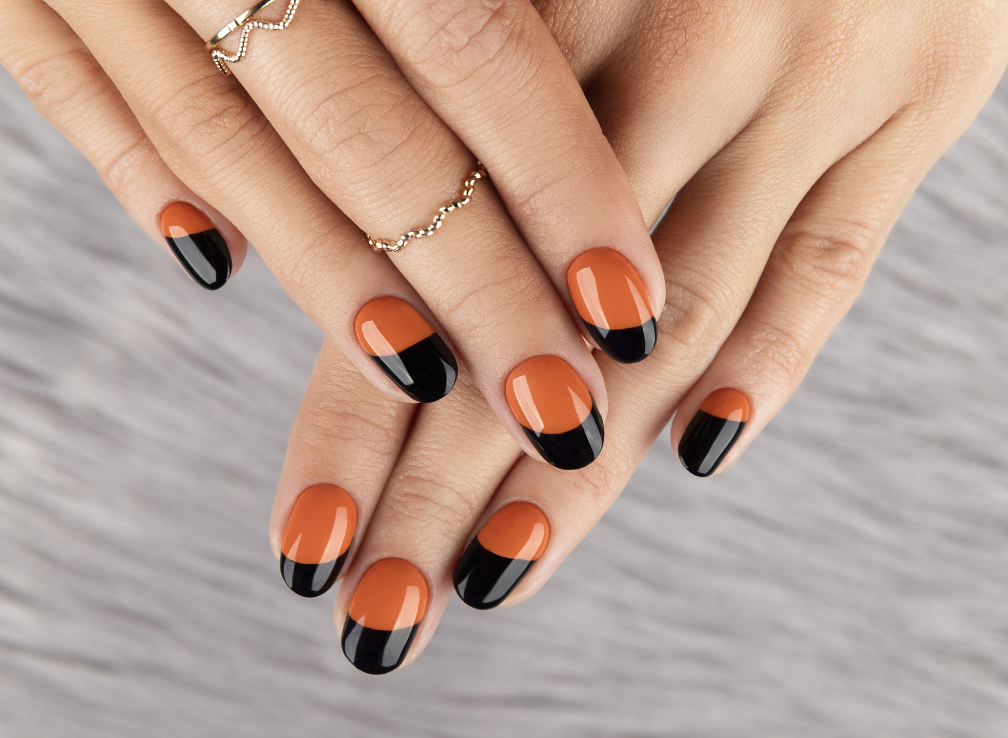 Manicured woman's hand over furry background. Trendy autumn halloween orange nail design.