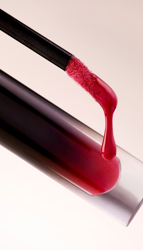 Applicatore di gloss rosso con texture brillante su sfondo chiaro