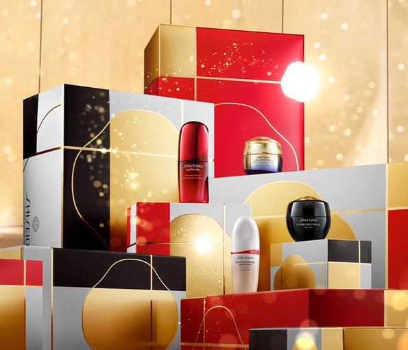 Shiseido confezioni regalo con prodotti skincare e trattamenti viso in eleganti box rosso, oro e nero su sfondo luminoso.