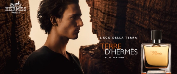 Boccetta di Terre d’Hermès Pure Perfume davanti a un paesaggio roccioso, con atmosfera calda e logo Hermès Paris in alto.