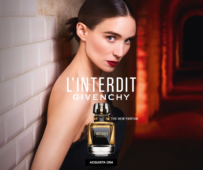Flacone profumo L’Interdit Givenchy su sfondo elegante con archi illuminati, testo L’Interdit Givenchy The New Parfum e pulsante Acquista ora.