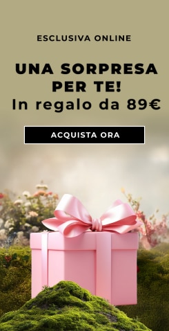 Scatola regalo rosa con grande fiocco posata su muschio, testo ‘Esclusiva online – Una sorpresa per te! In regalo da 89€’ e pulsante ‘Acquista ora’.