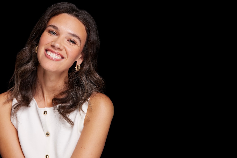 Top bianco senza maniche con bottoni dorati su sfondo nero.