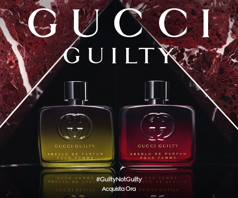 Due flaconi di profumo Gucci Guilty Absolu de Parfum Pour Homme e Pour Femme su sfondo marmo rosso, hashtag #GuiltyNotGuilty.