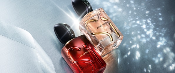 Giorgio Armani fragranze Sì in flaconi rosso e rosa con tappo nero su sfondo argentato luminoso.