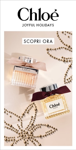 Chloé Joyful Holidays, due flaconi di profumo Chloé con fiocchi rosa e bordeaux tra decorazioni dorate, testo Scopri ora.