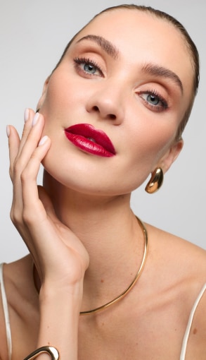 Collana rigida dorata e top con spalline sottili su sfondo chiaro.