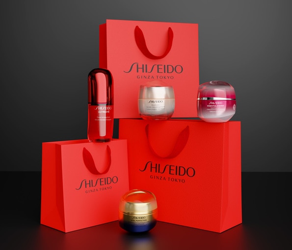 Eleganti confezioni regalo rosse con prodotti skincare Shiseido su sfondo scuro raffinato.
